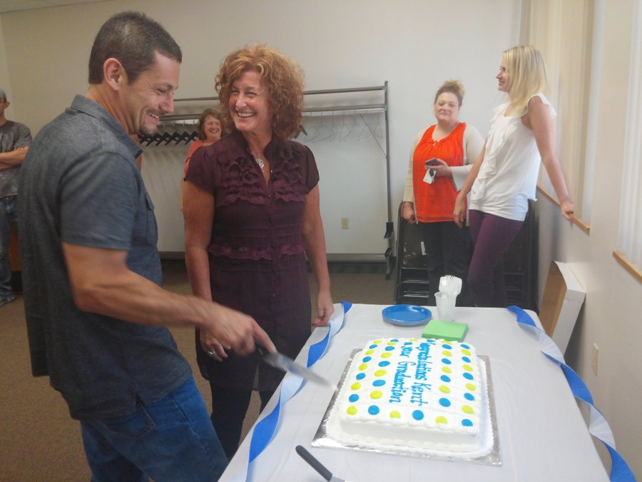 Kent Holden cuts his graduation cake while talking with his probation officer Rene Osborn.