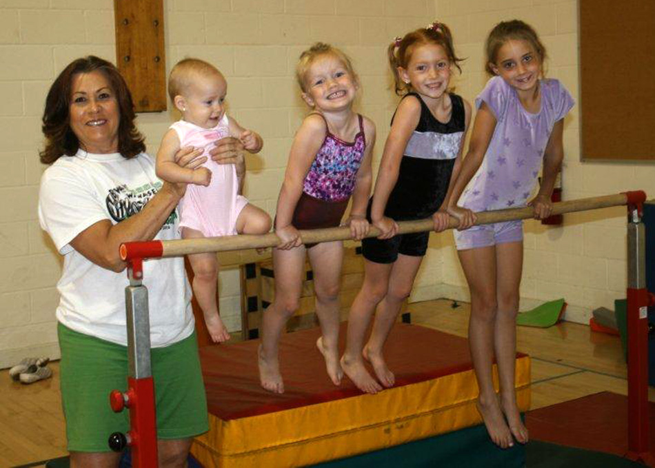 With huge smiles, Wawasee Gymnastics Club director Nika Prather works with campers (from left) Kaleigh Corn, Ashlyn Corn, Charlotte Crighton and Lily Crighton at the June 2013 camps.