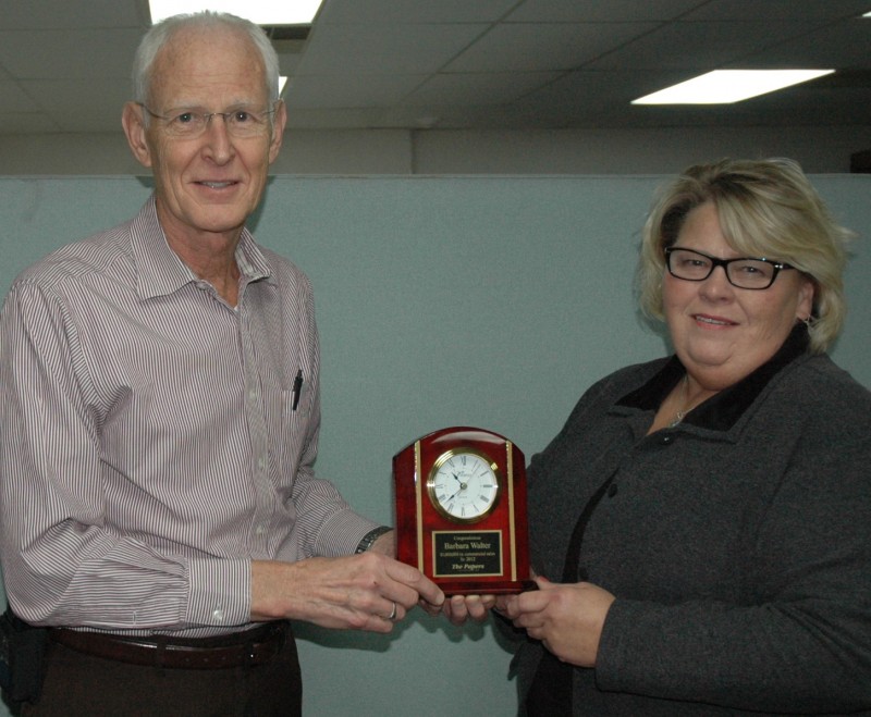 Ron Baumgartner, left, publisher of The Papers Inc. in Milford, recently presented a clock to Barb Walter, commercial printing account executive. Walter earned the clock by achieving $1 million in commercial printing sales during 2012 for The Papers. (Photo by Tim Ashley)