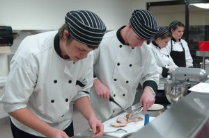 The culinary arts program at Wawasee High School gives students hands-on experience in food preparation and presentation using a professional-grade kitchen and equipment. Preparing a pork loin are Josh Secor and Cody Retcher. In the back are students Elaine Williams and Sara Christner.