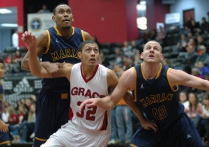 Freshman Brandon Vanderhegghen of Grace College, a Mishawaka native, battles for a rebound with a pair of Marian players at Grace Wednesday night (Photo provided by Grace College Sports Information Department)