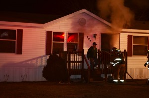 Firefighters enter the burning mobile home at Lot 128 in Green Acres Mobile Home Park. (Photo by Stacey Page)