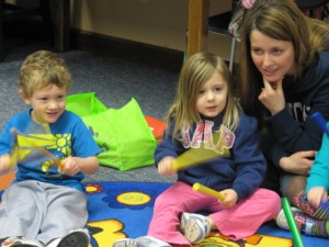 Counting time with the rhythm sticks are Liam Rumfelt and Leah Hurst. Mom, Sarah Hurst , enjoys the fun during Story Time at the Syracuse Library. (photo provided)