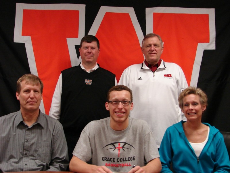 Warsaw's John Swanson will play basketball at Grace College next season. Swanson, in the middle of the front row above, is flanked by his parents Jim and Patti. In back are Warsaw coach Doug Ogle and Grace coach Jim Kessler (Photo provided)