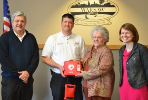 Joan Kizer and her granddaughter, Katie Maile, present Warsaw-Wayne Township Fire Chief Mike Brubaker with an AED unit for the fire department. Also pictured is Warsaw Mayor Joe Thallemer. 