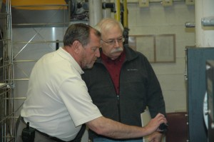 Doug Munz, left, of Energizing Indiana, assesses the boiler room as part of an energy assessment of Wawasee Middle School Tuesday. Also shown is Randy Johnson, energy management supervisor for the Wawasee Community School Corp. (Photo by Tim Ashley)