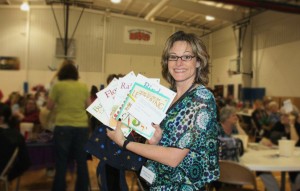 Kristen Heiman, iBOP member, showcases some books up for bid at the April 28 quarter auction sponsored by the networking group. More than $2,000 was raised to support the Baker Youth Club. (Photo provided)