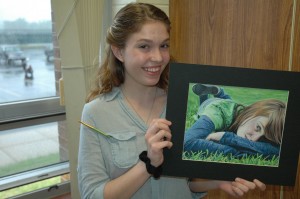 Alexis LeCount, a student at Wawasee High School, is holding a self-portrait she drew with colored pencils that will be displayed at the school’s annual art show. (Photo by Tim Ashley)