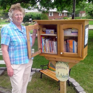 Ann MConnell stands next to the lending library she has made available at the end of her driveway on School Street, Leesburg