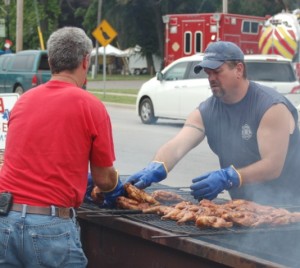 Brad Simmons and Chris Fancil, Turkey Creek Fire Territory firefighters, take chicken halves off the grill