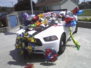 Akron Town Marshal Tim Fleck's patrol vehicle is covered with flowers and other tokens of remembrance left in his honor. (Photo provided by John Adams)