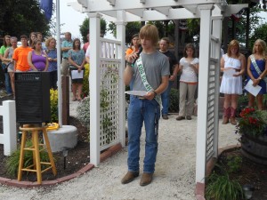 Vice President of Junior Leaders, Cody Demske recalls the history of the Memorial Gardens during the 20th Anniversary Re-dedication while other Junior Leaders and 4-H members and leaders look on. (Photo by Stephanie Loney)
