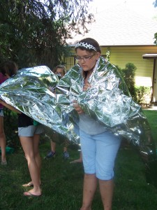 Austi Swanson learns how to keep herself warm using an aluminum blanket during the Unofficial Hunger Games Program sponsored by the Milford Public Library. (Photo provided)