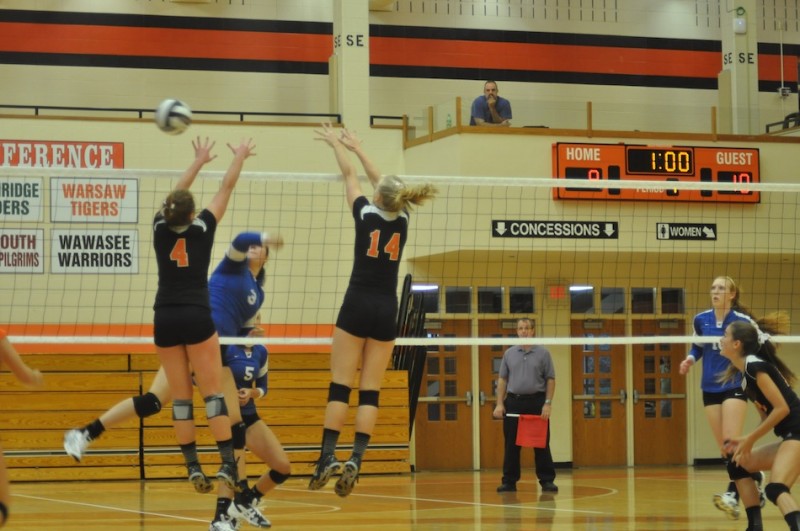 Warsaw's Emily Poe and Katie Voelz attempt to block a Marian hitter Monday night (Photo by Amanda Farrell)