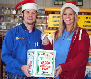 Tim Bowling, left, and Dawn Pelikant, NAPA Auto Parts, Syracuse, show how to enter the Christmas Bucks Contest. (Photo by Martha Stoelting)