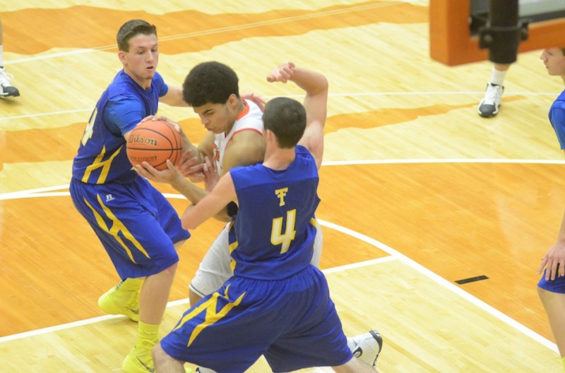 Warsaw's Rashaan Jackson is bottled up in the lane by Joey Corder (No. 4) and Tanner Shepherd of Triton.