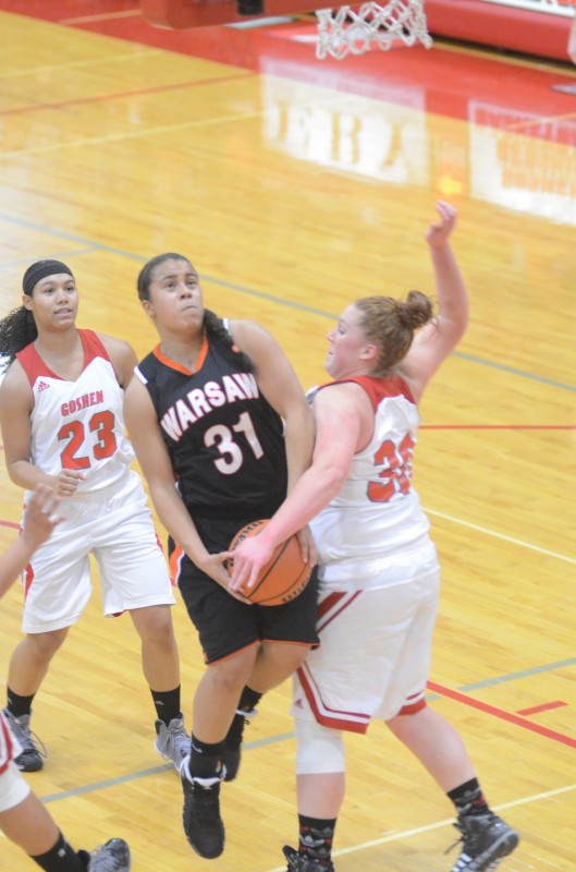 Warsaw senior Brooklyn Harrison is met in the lane by Jessica DeStefano of Goshen Saturday night.