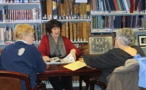 Beth Smith (center), director of the Library’s Local History and Genealogy Center, explains to Faye Myer (left) and Becky Pressler (right) how to identify old photos during last week’s Glean Team. This group meets at 10 a.m. the first, second, and third Wednesdays of each month to collaborate on genealogy projects. (Photo provided)