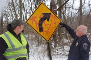 Kosciusko County Sign Technician Jeff Beeler, left, and gang specialist Officer Mike Cox, Warsaw Police Department, discuss the meaning of symbols painted on a sign on Hoss Hill Road, North Webster. The road is full of signs the county will have to replace due to gang-related tagging.