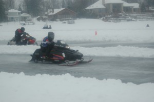 A pair of snowmobilers go head-to-head down the icy drag strip.