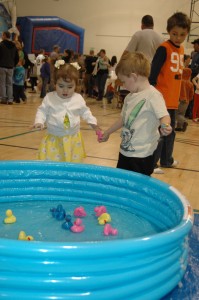 Isabelle Caudill, 17 months, daughter of Dona and Norma Caudill, North Webster, and Maddox Fatchett, 2, son of Megan ad Cole Fatchett, North Webster, pick plastic ducks to trade in for prizes during the Easter celebration at the North Webster Community Center Saturday morning. Caudill was unsure of the water in the pool, so Fatchett decided to lend a hand. (Photo by Amanda McFarland)