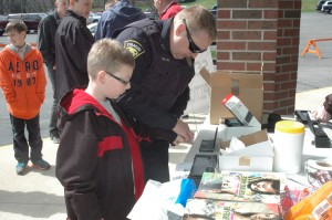 Colton Edger, front, gets his fingerprints taken by Syracuse Reserve Officer Joe Keene during last year’s Safety Day event, which was held on a brisk April Saturday. This year’s Safety Day will be from 10 a.m. to 2 p.m. Saturday, May 3. (File photo)