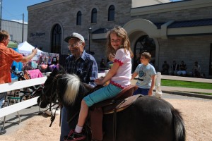 Cap Beer helps Isabel Schwartz, 7, on the pony ride at today's Milford Fest. 