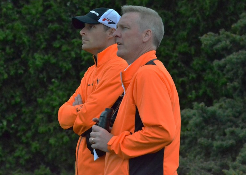 Warsaw head coach Ben Barkey (left) looks on with Steve Hollar as Warsaw's Jonny Hollar tees off on No. 18 on Tuesday night.