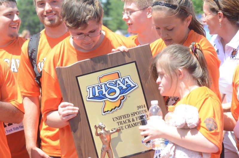 Members of the Warsaw Unified track team admire their state championship trophy Saturday in Bloomington.