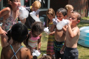 The Syracuse Library was lucky to have a hot day to explore water science on Tuesday, July 22. Kids are shown learning about the surface tension of water. Squirt guns, water rockets, beach balls and wading pools were used to investigate other water properties. (Photo provided)