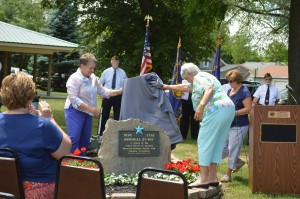 After months of work, the Syracuse-Wawasee had a Blue Star Memorial placed in Veteran’s Memorial at Crosson Mill Park Sunday afternoon. Shown are Carol Koble, left, and Jo Butler unveiling the marker which has been placed by the cannon in the park. Approximately 50 people attended the dedication ceremony. (Photo by Lauren Zeugner)