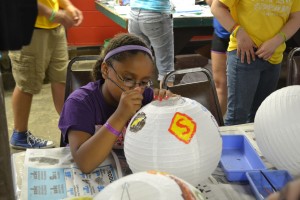 Molly Greer focuses on her work as she paints superhero logos on her lantern during arts and crafts at Deaf Camp.