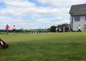 Warsaw Community High School boys golf coach Ben Barkey, in the pink top, works with junior golfers at a golf camp at Stonehenge.