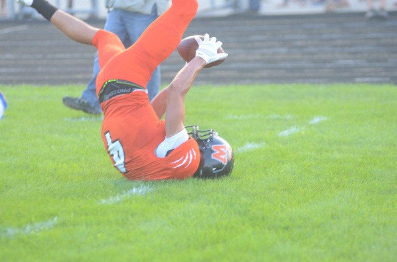 Warsaw's Riley Rhoades lands upside down trying to make a catch Friday night.