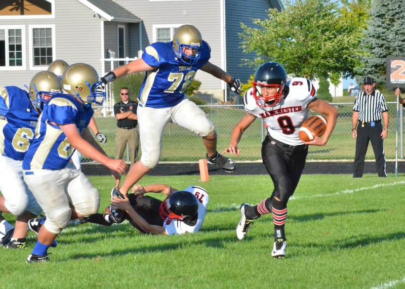 Remington Trick (9) attempts to run the option for Manchester while Ryan Horne (72) goes airborne in pursuit for the Trojans. (Photos by Nick Goralczyk)