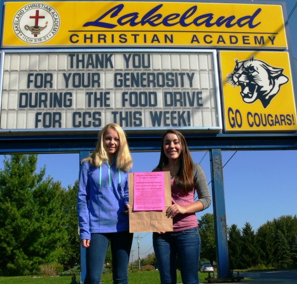 Lakeland Christian Academy students Baylee Wiley (left) and Veronica Flores (right).  They are holding one of the 5,000 bags donated by Owens Supermarket that the LCA students will be distributing today.
