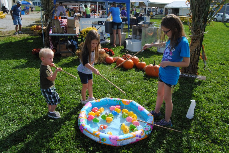 Braiton Spivey, Audrey Musgrave and Elliette Pulley try to reel in a “fish” at today’s North Webster Heart of the Harvest Fall Festival.  (Photo by Phoebe Muthart) 