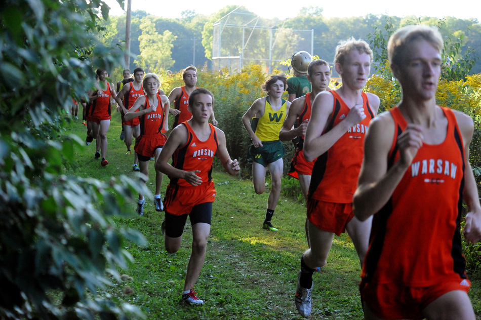 Members of the Warsaw and Wawasee cross country teams stampede up the straightaway at Wawasee.