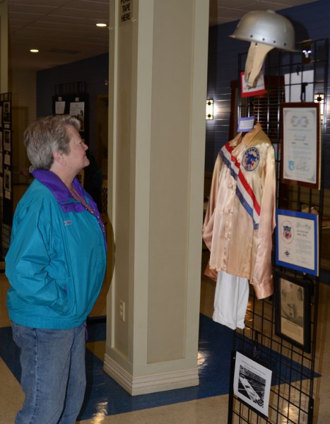 Sherry Carey takes a look at Steve Lewis' uniform and other memorabilia from his Soapbox Derby participation. (Photo by Deb Patterson)