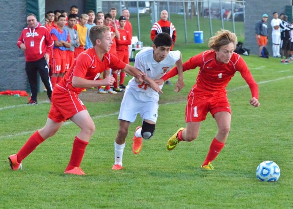 Tito Cuellar (center) is held back by Plymouth's Doug Overmeyer and Jacob Hildebrand in the first half of Wednesday's semi-final contest.