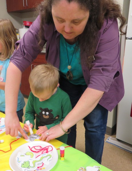 Youth Librarian Mrs. Pam helps James Stull with his craft during Preschool Story Time.