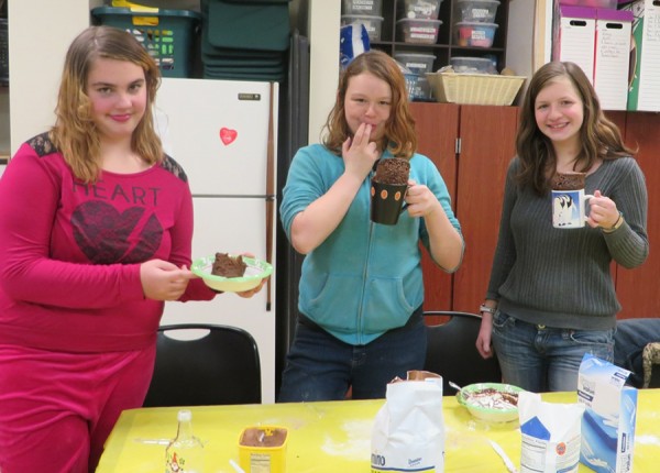 Samantha Trott, Anita Denney, and Rachel Fishburn sample their Christmas mug cakes they made during last week’s Teen Time.