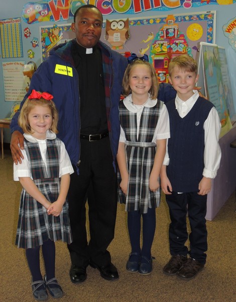 Pictured from left to right are Dauren, Dalaney and Daylor posing for a picture with Father Raynould after visiting with him in a kindergarten room taught by Monica Smith during the school open house.