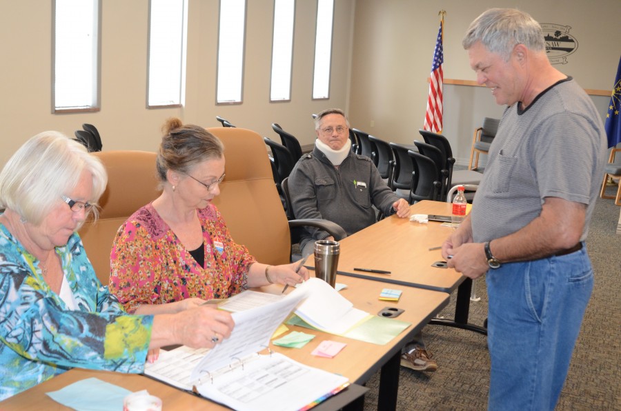 Warsaw 2-2 Poll clerks Susanne Robinson and Carol Volkers check their records for resident Ronald G. Donkers, on the right, to have him officially sign in. Jerold Nelson, judge is shown in the background. (Photo by Deb Patterson)