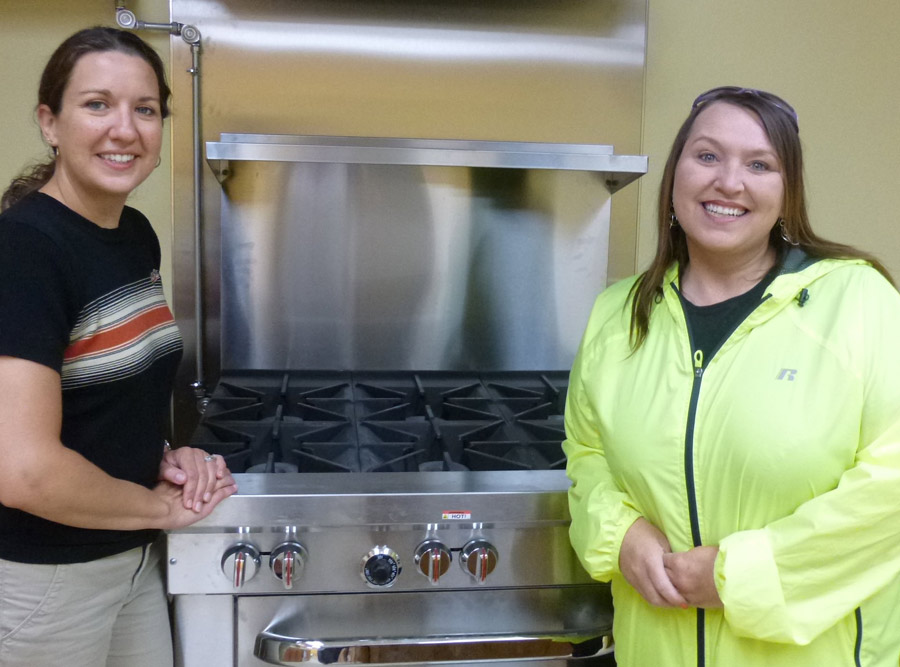 Beaman Home’s Executive Director, Tracie Hodson, and Outreach Program Coordinator, April Slone, stand next to Beaman Home’s new commercial grade stove in the kitchen of the new Beaman Home Outreach Center. 