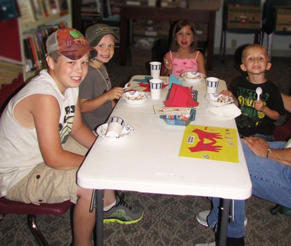 Wyatt Haab, Westen Haab, Macy Morehouse, and Owen Morehouse enjoy a scoop of ice cream at snack time after story hour on July 24.