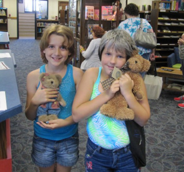 Every week children can shop at the Syracuse Library with money they earn from reading. Esther Whirledge and Ivy Wiggs chose bears. The bears in the case were donated by Janet Krull. The gifts from other organizations have made it possible to offer these rewards.