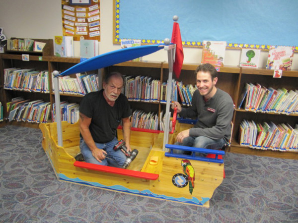 The boat is ready to sail. All it needs is a name and some smaller children to make it sail. Making a test run are Jay Vore, volunteer at the Syracuse Library, and staff member, Austin Meerzo. 