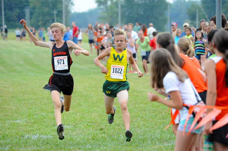 Warsaw's Nathan Gottschalk lunges at the finish line to edge Wawasee's Ben Hoffert for the point at the two competitors finished at 19:01 in the Northern Lakes Conference dual Tuesday at Warsaw. The Tiger boys and girls both beat Wawasee in the team standings. (Photos by Mike Deak)