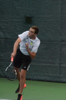 Justin Stout follows through on a serve in doubles play.